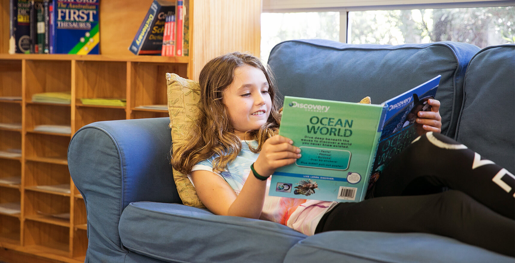 Rockingham Montessori School female student reading a book while laying down on the couch