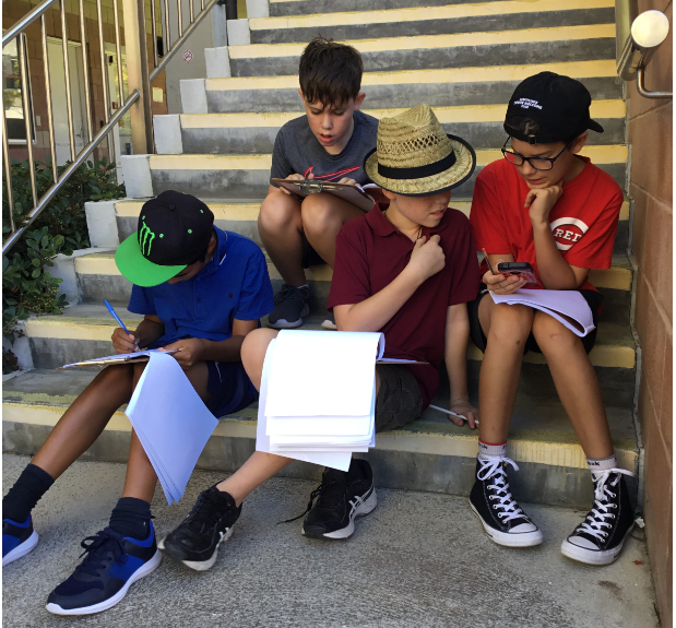 Rockingham Montessori School boys seated on the staircase while working on worksheets