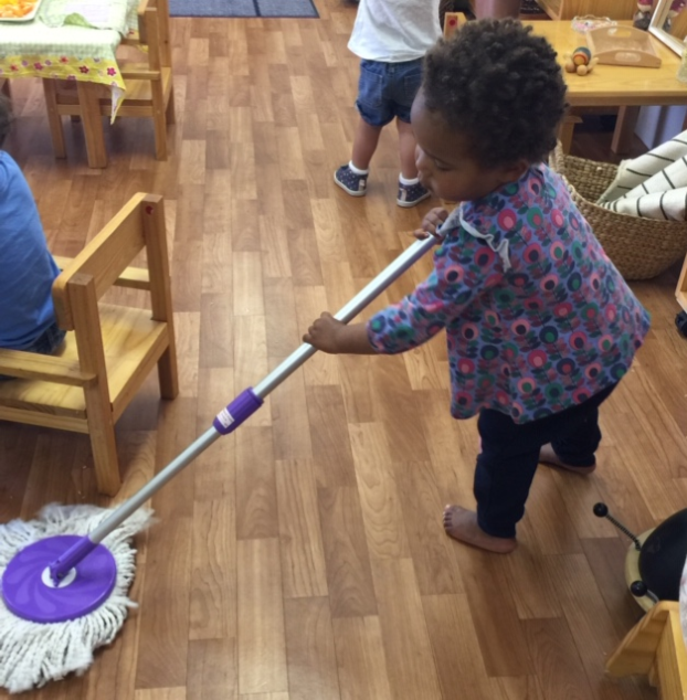 Rockingham Montessori infant toddler sweeping the floors while barefoot