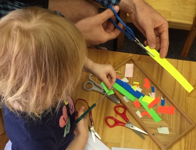 Rockingham Montessori School infant toddler cutting small papers to develop his motor skills