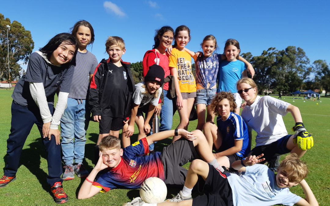 Rockingham Montessori male and female students striking a photo in the field after playing football