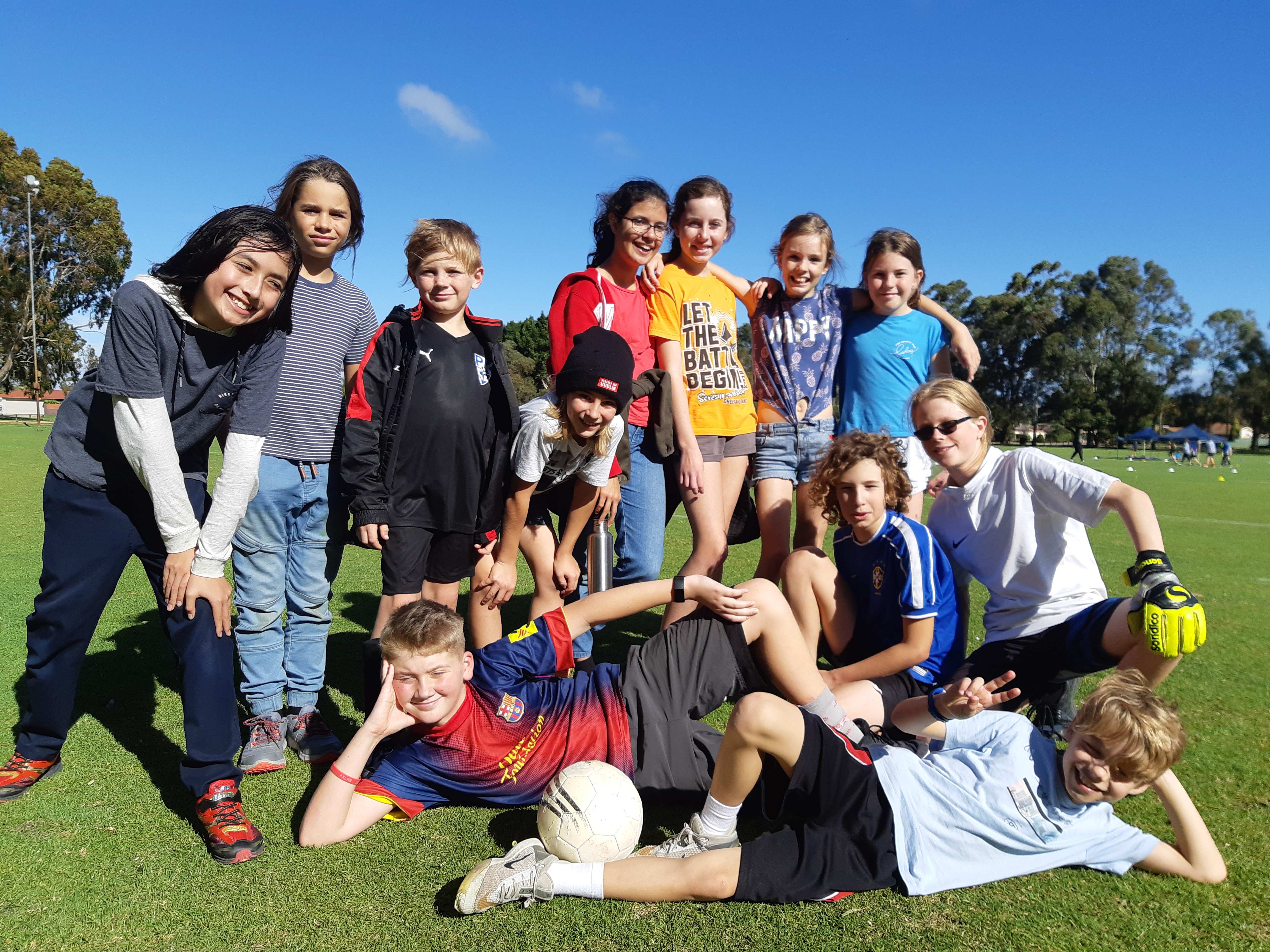 Rockingham Montessori male and female students striking a photo in the field after playing football