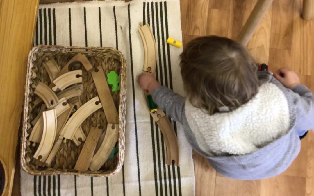 Rockingham Montessori infant toddler playing with wood puzzles on the floor