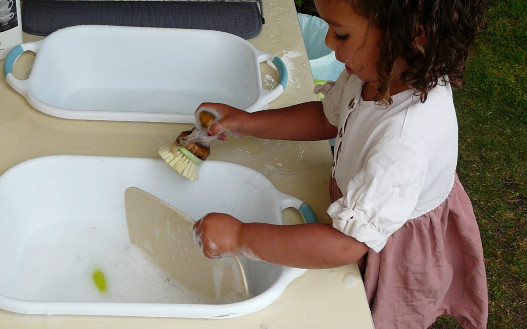 Rockingham Montessori infant toddler student washing a board in the sink