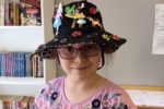 Rockingham Montessori student wearing a hat with characters during Upper Primary's art showcase