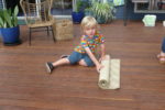 Rockingham Montessori male student rolling a mat on the floor
