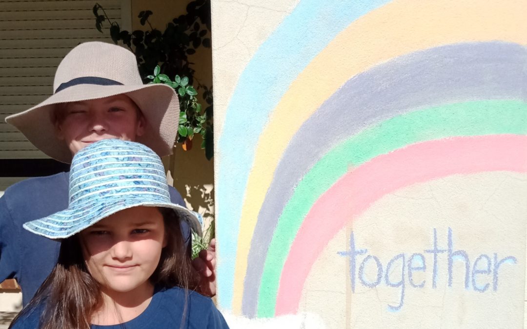 RMS students wearing hats posing with a rainbow art on the wall