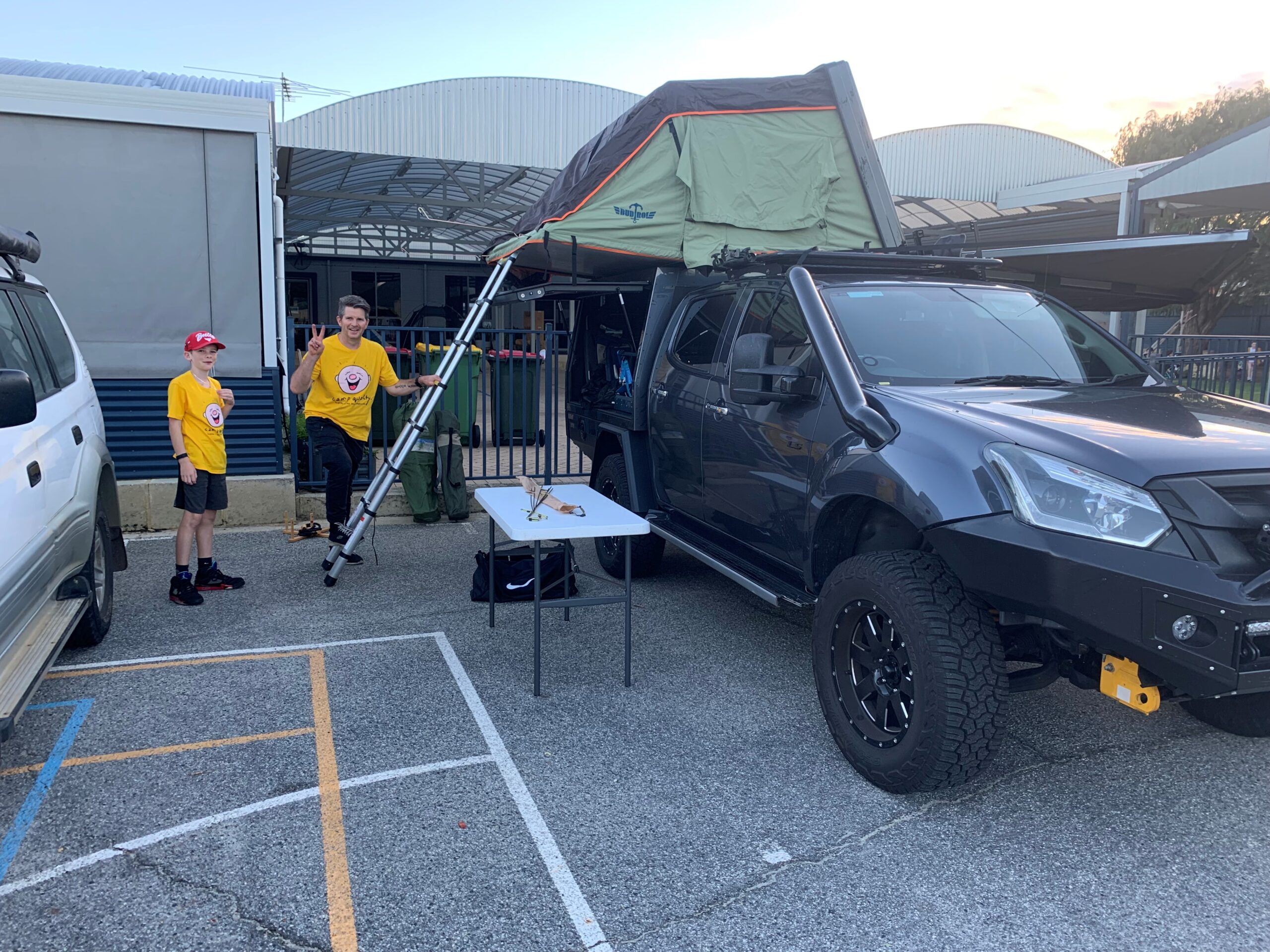 Rockingham Montessori male students taking a photo beside a camp trail vehicle