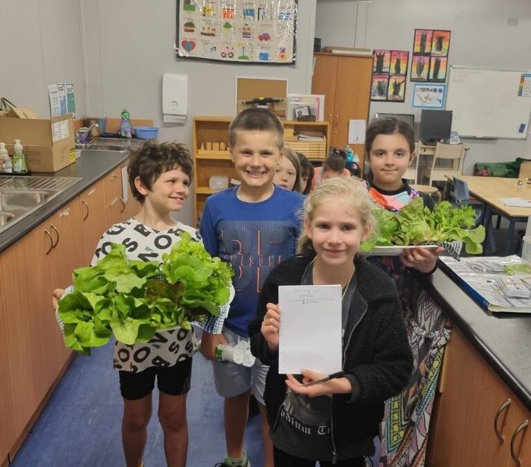 Children holding produce from veggie garden at Rockingham Montessori